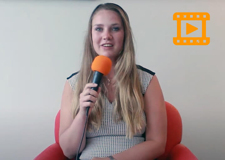Vrouwelijke student houdt een oranje microfoon vast gedurende haar stage interview
